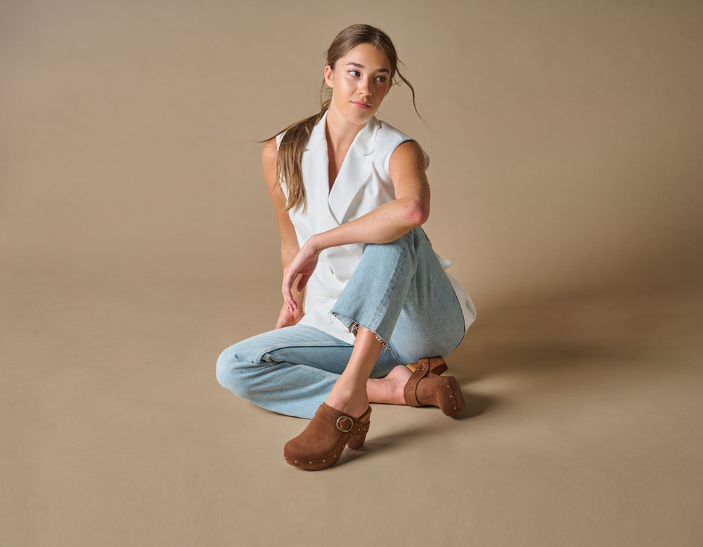 A woman wearing the Gemini heeled clog in Brown Suede.