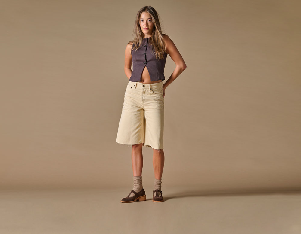 A woman wearing the Jesse low-heeled shoe in brown suede.