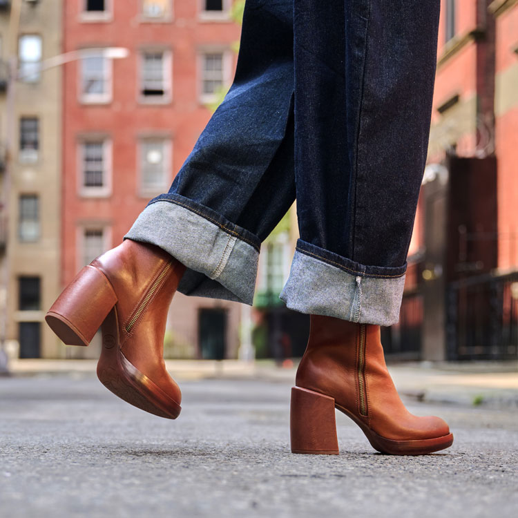 A woman wearing the Aime heeled ankle boot in rust (brown). Shop Aime.