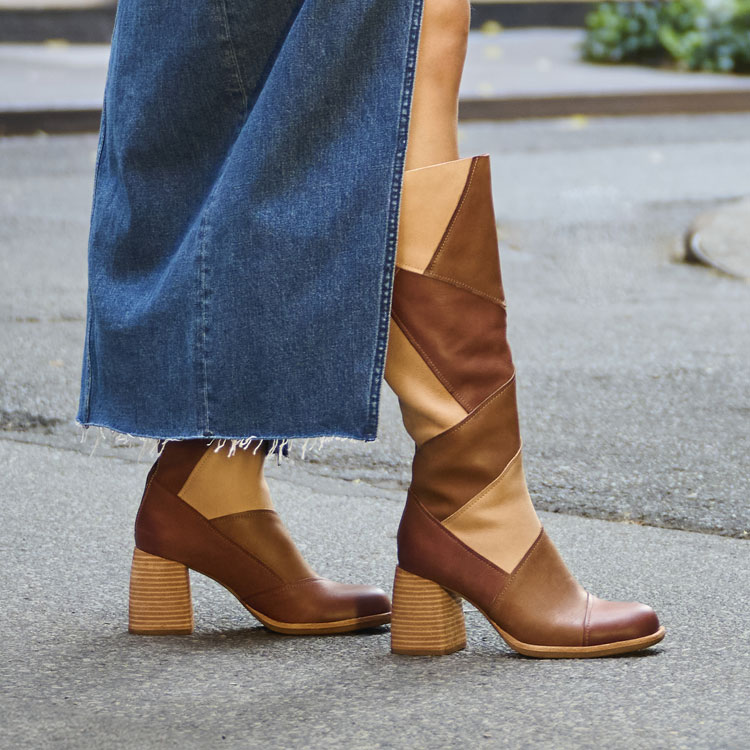 A woman wearing the Asbee heeled tall boot in tan brown combo. Shop Asbee.